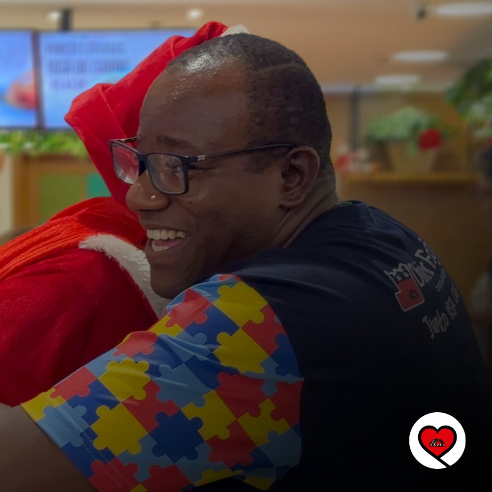 Voluntário do Divino Fogão sorrindo e abraçando o Papai Noel